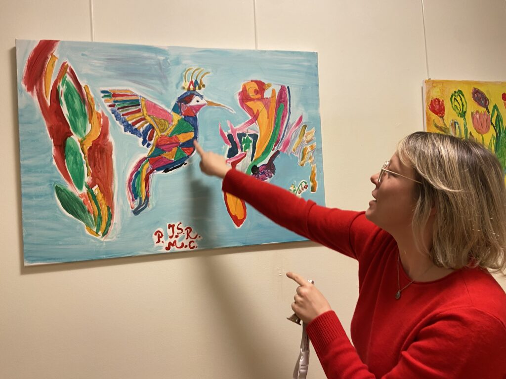 Eine Frau zeigt auf ein Bild an der Wand