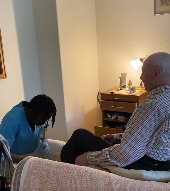 Deen hilft Patientem beim Schuhe anziehen