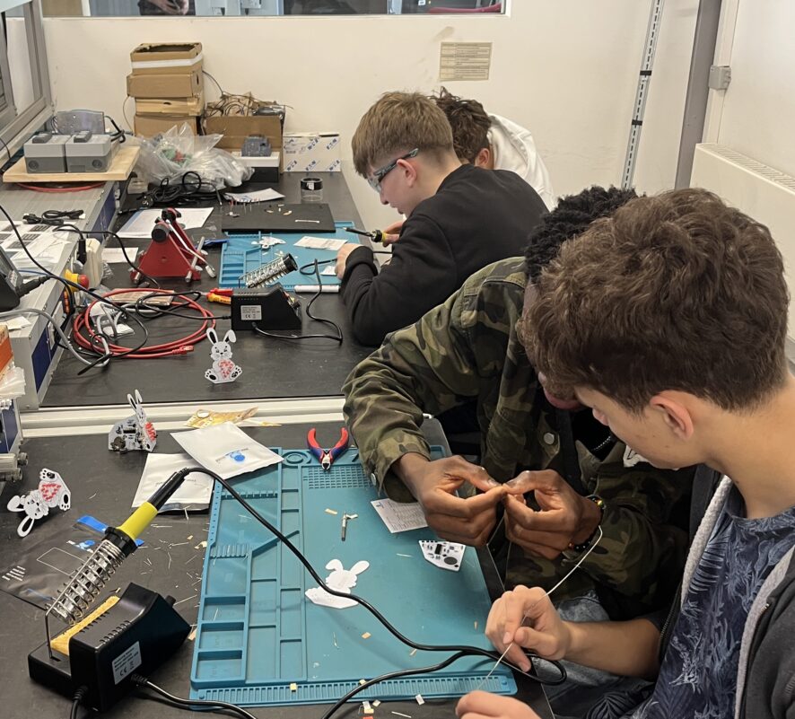 Interessierte Schüler arbeiten an einem Tisch an Elektronikteilen